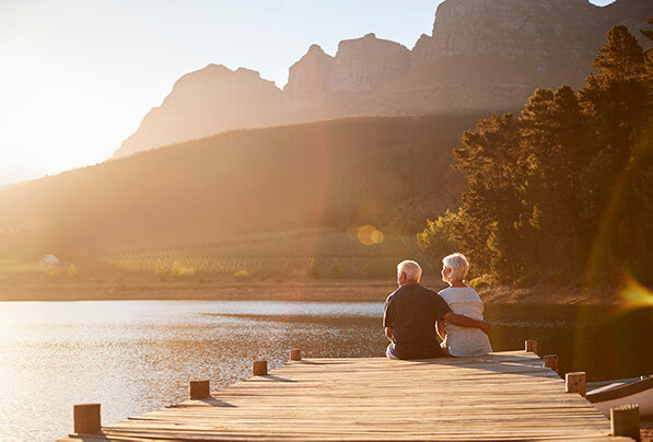 Couple sitting on a pier watching the sun set over a lake